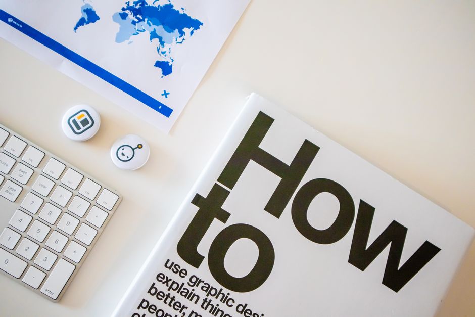 Configuração de mesa estilosa com um livro de como fazer, teclado e mapa-múndi em papel.