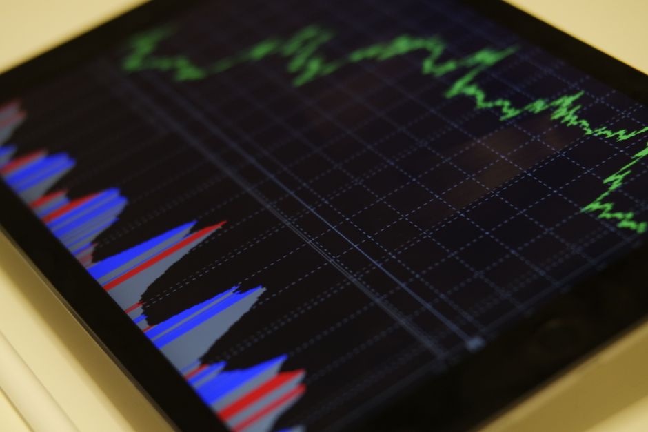 Close-up de um tablet exibindo análise do mercado de ações com gráficos coloridos.